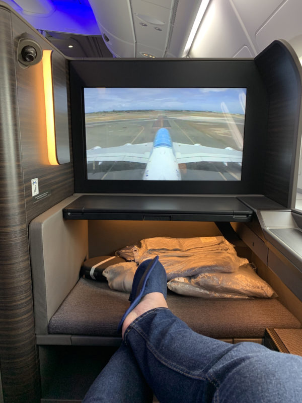 a person's feet in a seat with a television in the back