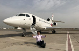 a man sitting on the ground next to an airplane