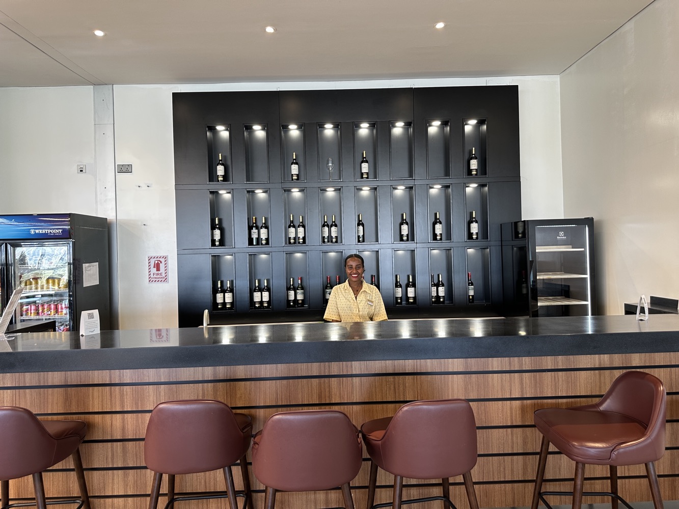 a woman behind a counter in a room with wine bottles