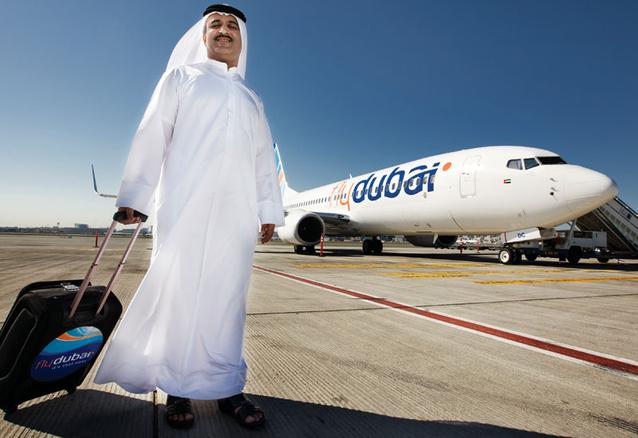 a man in a white robe with a suitcase standing in front of an airplane