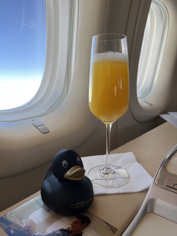 a glass of orange liquid next to a rubber duck on a table