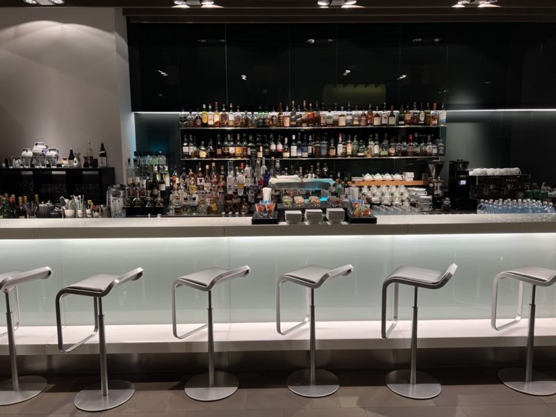 a bar with a row of stools and bottles