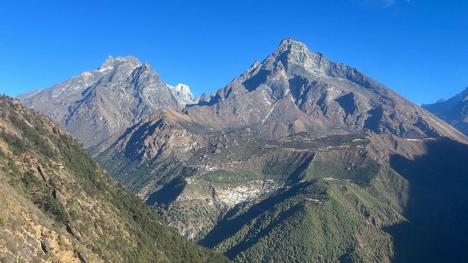 a mountain range with trees and blue sky